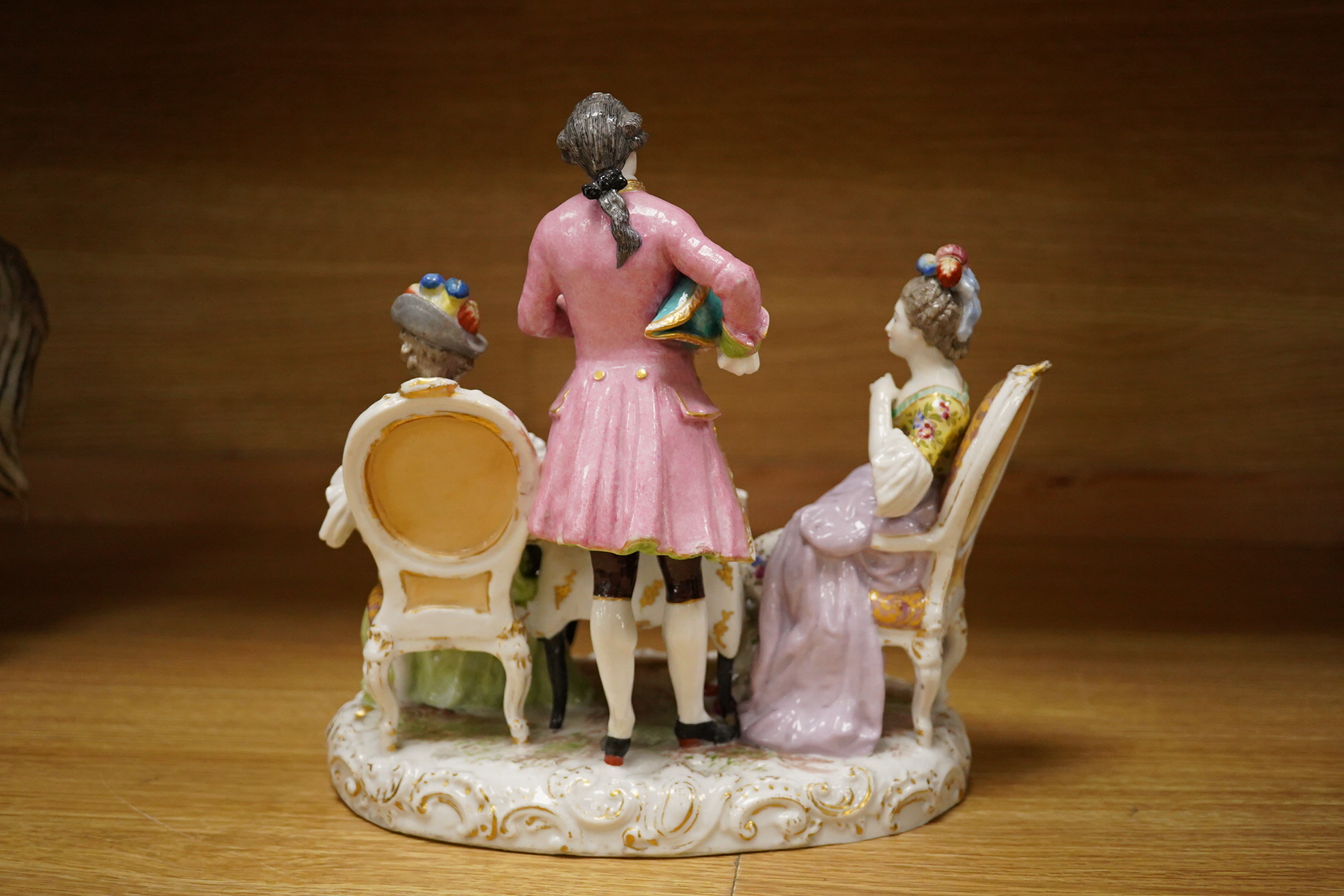 A 19th century Dresden porcelain group of three figures at a table, 24cm high